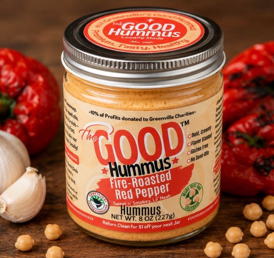 Jar of The Good Hummus Fire-Roasted Red Pepper Hummus with ingredients on a wooden surface