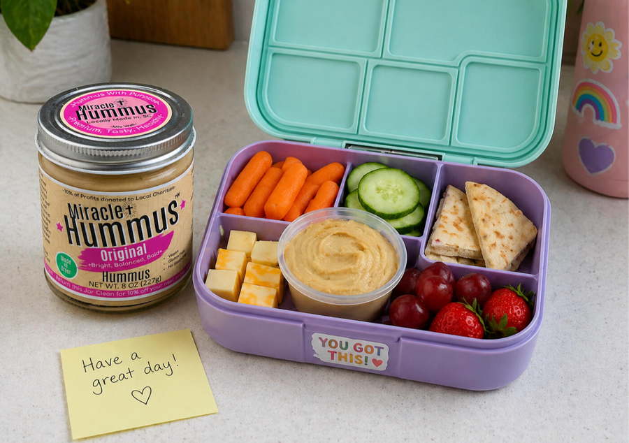 Bento box with snacks and a jar of Good Hummus on a table.
