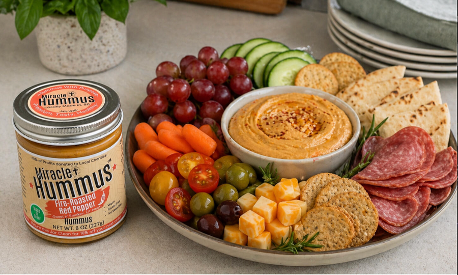 Platter of snacks including a jar of Good Hummus, fruits, vegetables, and cheese.